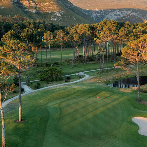 Golf course with green grass, trees, and mountains in the background