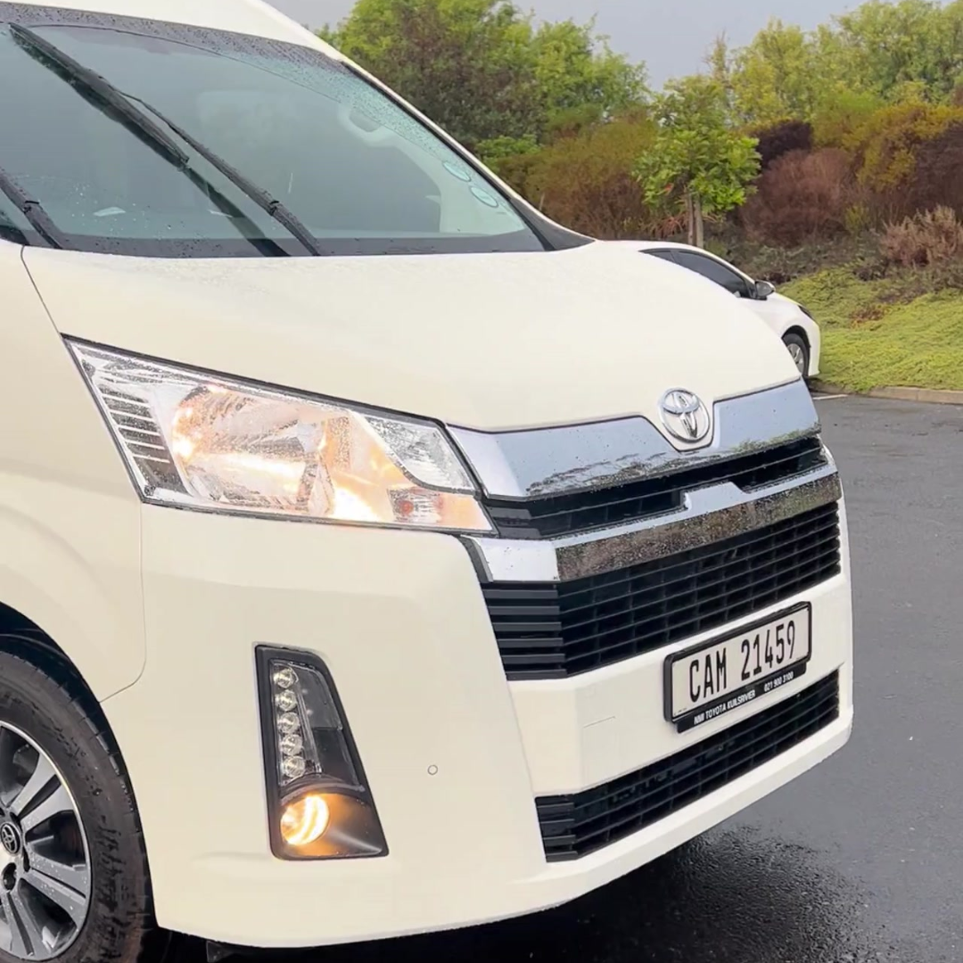 White Toyota van on a road with greenery in the background