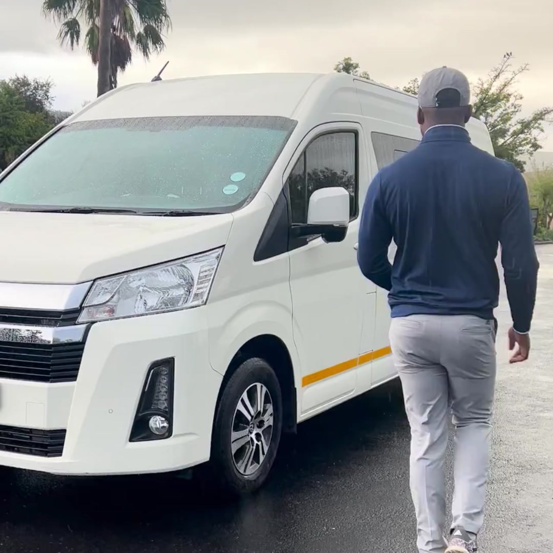 Man walking towards a white van on a road with trees in the background